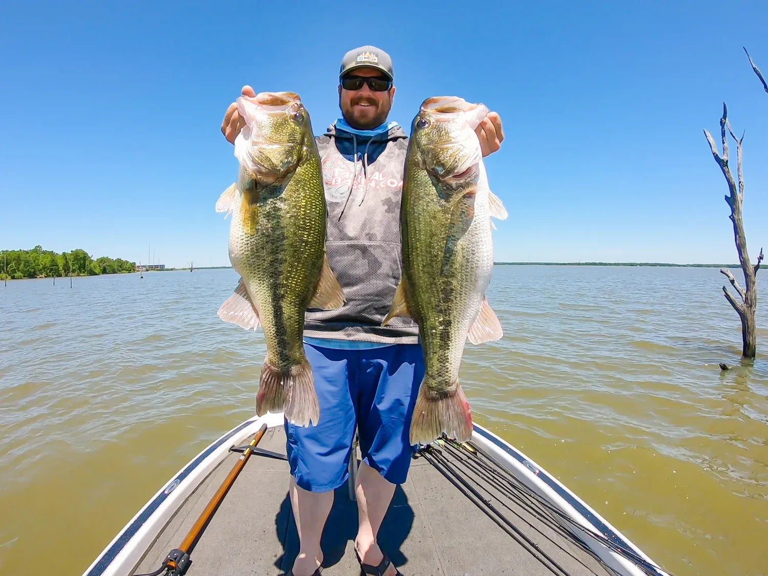 Angler proudly holding a double-digit largemouth bass from Lake Fork, with flooded timber in the background.