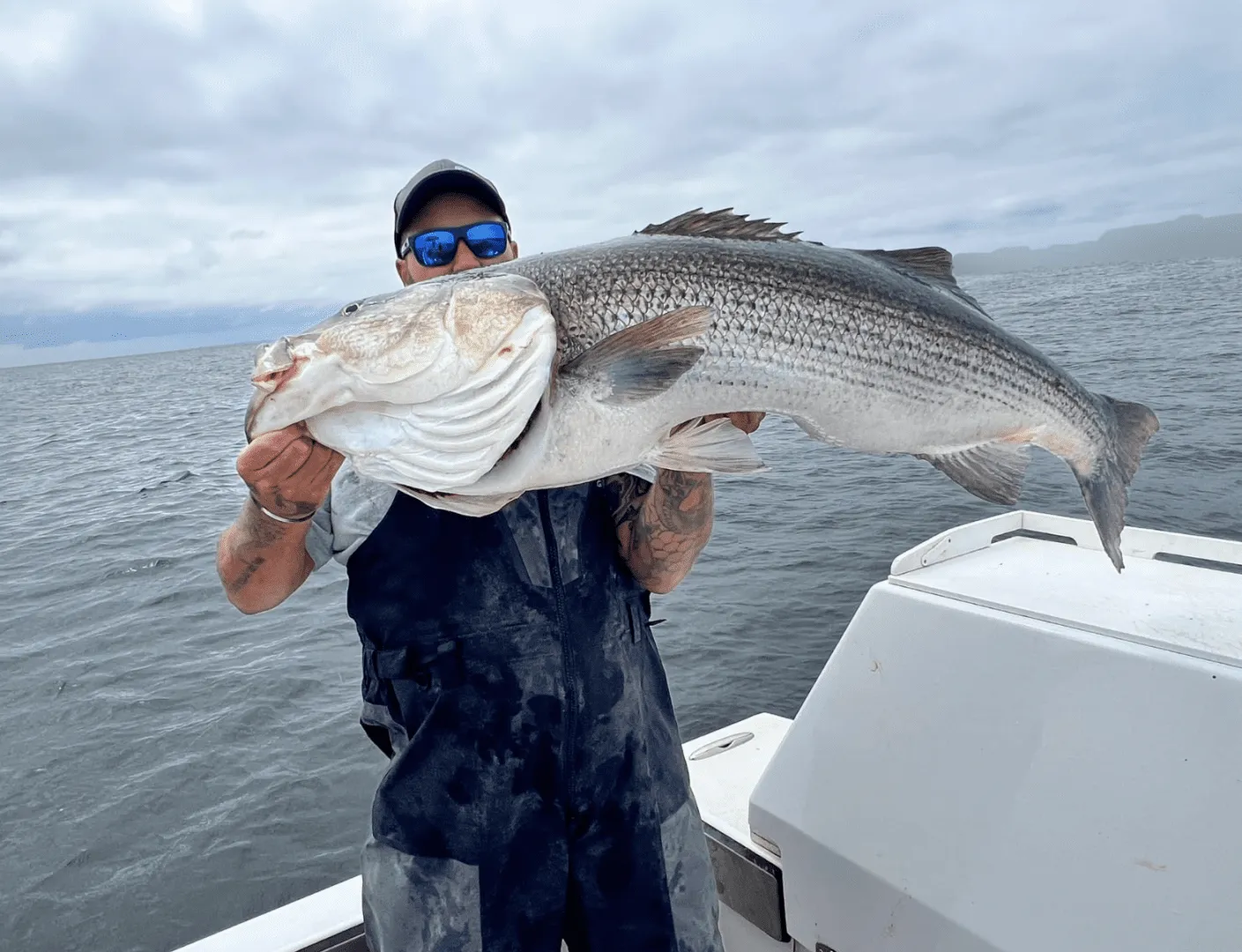 Angler proudly holding a large Striped Bass.